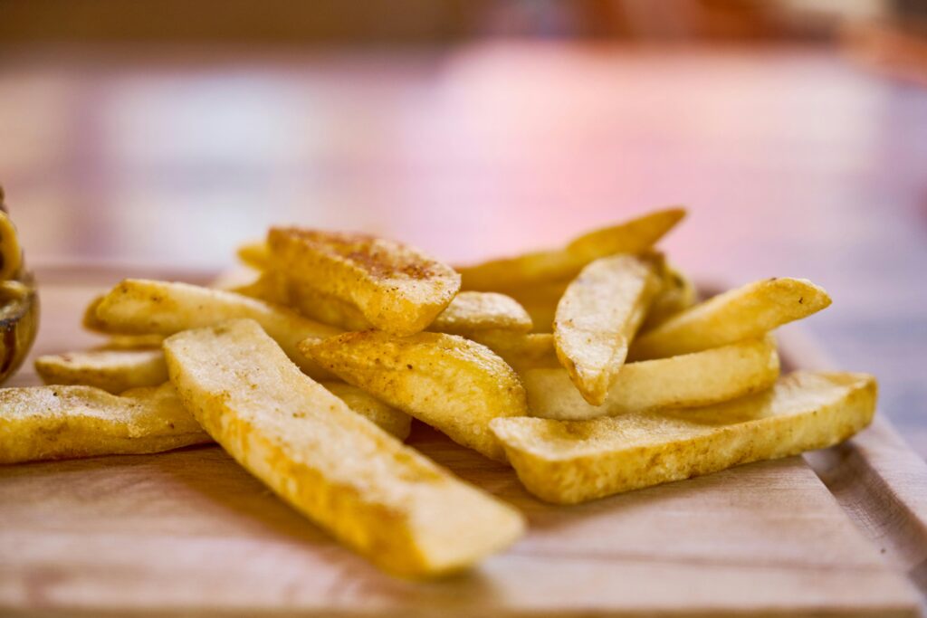 Crispy golden french fries on a wooden surface, ready to eat.